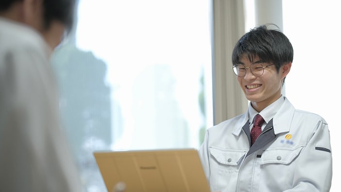 男性社員がノートパソコンを見ながら、向かいの人物と笑顔で話している面談の様子を写した写真