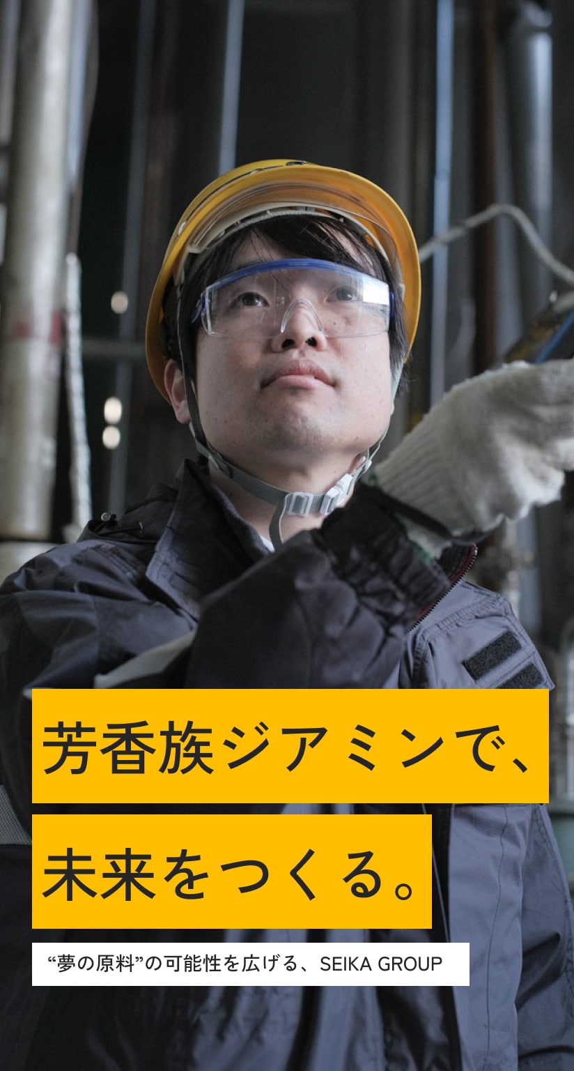 工場の設備をリモコンで操作する男性社員の写真。ヘルメットと安全ゴーグル、軍手、作業着を着用している