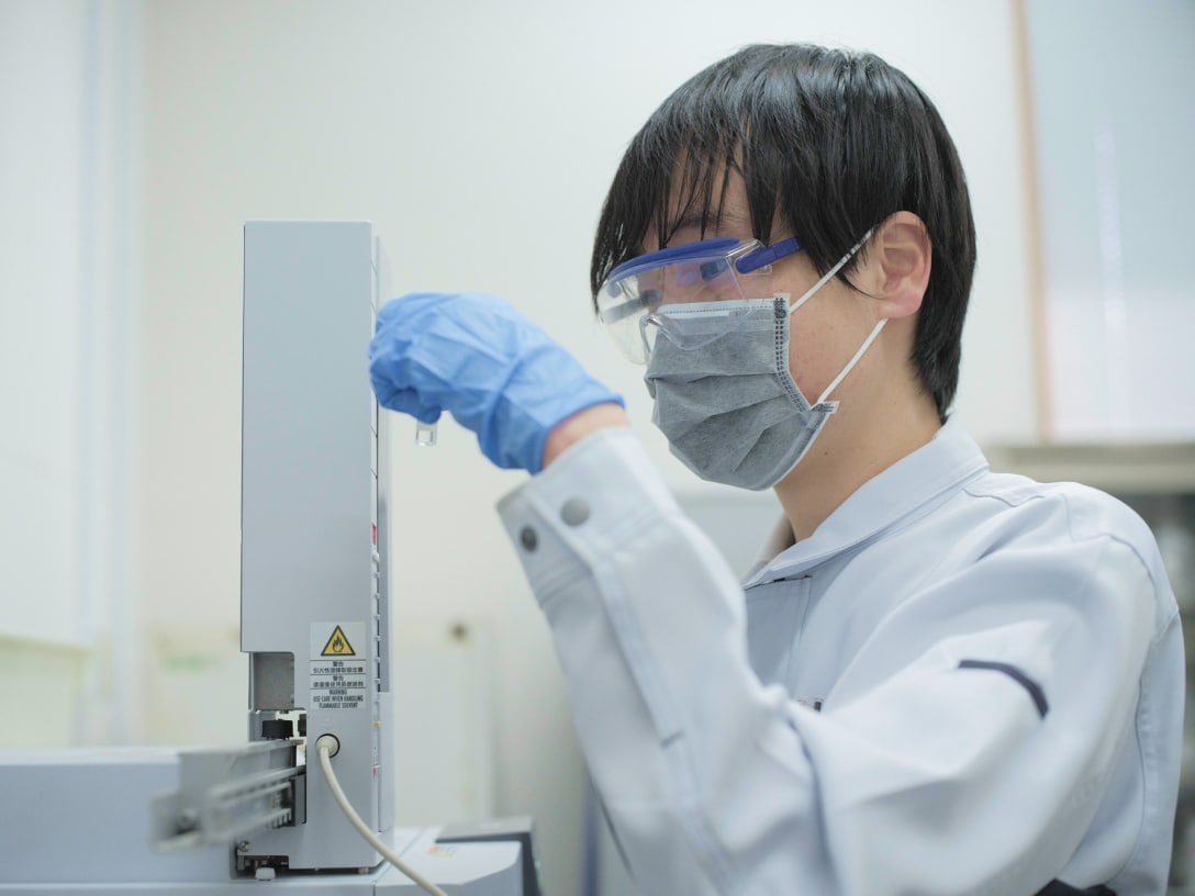 実験を進めるR.Sさんの写真。安全ゴーグルとマスク、ゴム手袋、ユニフォームを着用している